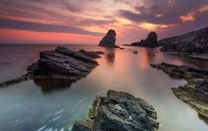 a sunset over the ocean with rocks in the water at Sweet Suite Sinemorets in Sinemorets