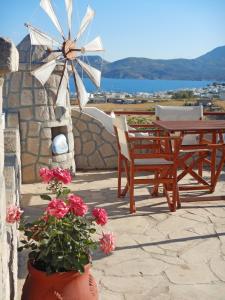 eine Terrasse mit einem Tisch, einer Windmühle und Blumen in der Unterkunft Christos rooms milos in Adamas