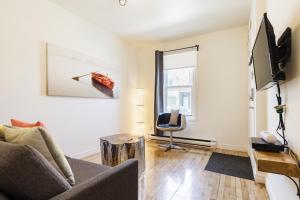 uma sala de estar com um sofá e uma televisão em Espace Couronne by Hébergements DCL em Cidade de Quebec