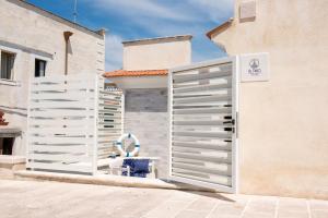 a white gate with a blue chair in front of a building at Al Faro Guest House in Vieste