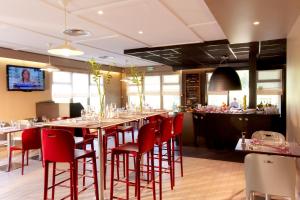 a restaurant with a long table and red chairs at Campanile Hôtel Auch in Auch