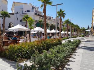 une rue avec des palmiers, des tables et des parasols blancs dans l'établissement Estudio central en zona petonal y cerca a la playa, à Torremolinos