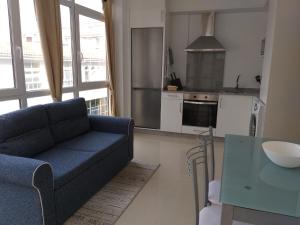 sala de estar con sofá azul y cocina en Apartamento en Ribeira(centro) 2* planta en Ribeira