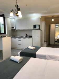 two beds in a kitchen with white cabinets and towels at White-House in Ureki