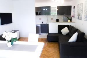 sala de estar con sofá negro y cocina en Villa Silvija en Mlini