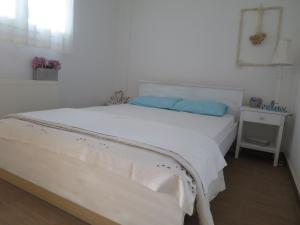 un letto bianco con cuscini blu in una camera da letto di Guesthouse with Garden a Komotini