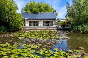 una casa con un estanque de lirios en La Ferme de L'Oudon & SPA, en Berville