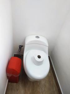 a white toilet in a bathroom with a red trash can at Anais y Nicolas Hostel Cusco in Cusco