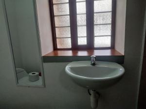 a sink in a bathroom with a window and a mirror at Anais y Nicolas Hostel Cusco in Cusco