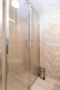 une douche avec une porte vitrée dans une salle de bain dans l'établissement Apartamenty Bieg, à Ustka 27 autres photos