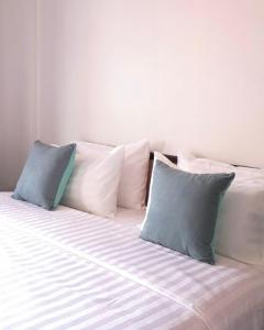 een wit bed met vier kussens erop bij RoongThoeng Heritage Hotel in Thoeng