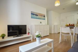 uma sala de estar com uma televisão e uma mesa branca em Apartamento Sol y Mar I em Las Galletas