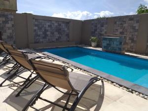 - une piscine avec 2 chaises à côté dans l'établissement Villa Oceane, à Pereybere