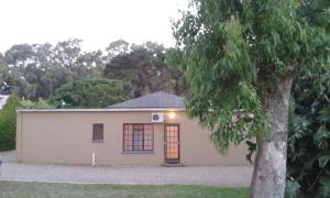 ein kleines Haus mit einem Baum davor in der Unterkunft Pine Tree Lodge PE in Port Elizabeth