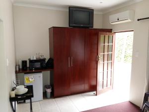 una cucina con TV sopra un armadio in legno di Pine Tree Lodge PE a Port Elizabeth