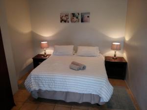 ein Schlafzimmer mit einem weißen Bett und zwei Nachttischen in der Unterkunft Pine Tree Lodge PE in Port Elizabeth