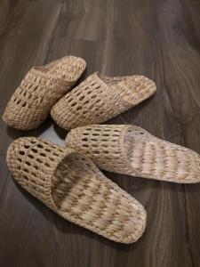 drie paar rieten schoenen op een houten vloer bij RoongThoeng Heritage Hotel in Thoeng