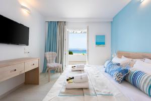 a bedroom with a large bed with a flat screen tv at Saint George Hotel in Chrissi Akti