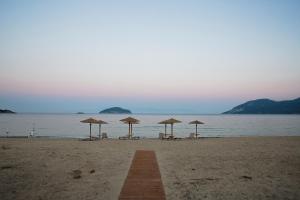a beach with chairs and umbrellas and the ocean at Rent House Karavi in Iraklitsa