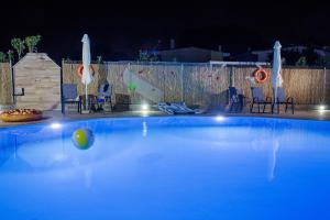 a blue swimming pool at night with chairs and a ping at Rent House Karavi in Iraklitsa