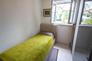 Dormitorio pequeño con cama con manta amarilla en Villa Mario, en Rogoznica