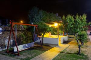 a park with a swing and a house at night at Rent House Karavi in Iraklitsa