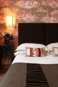 a bedroom with a large bed with a red and white wallpaper at Hotel Louison in Paris