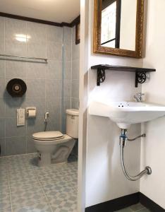 a bathroom with a toilet and a sink and a mirror at RoongThoeng Place Hotel in Thoeng