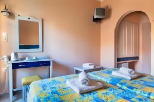 a room with two beds and a sink and a mirror at Rea Hotel in Palaiochora