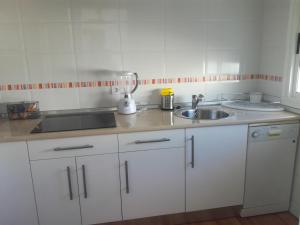 una cocina con armarios blancos y una licuadora en una encimera en BUNGALOW CHARO, en Torre de Benagalbón 11 fotos más