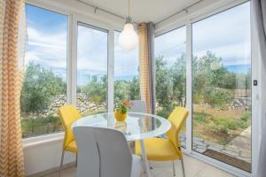 a dining room with a glass table and yellow chairs at Vila Lila in Drvenik Mali