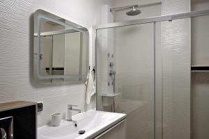 uma casa de banho com um lavatório e um chuveiro com um espelho. em Apartament Uśmiech em Ustrzyki Dolne
