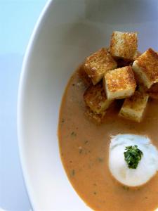 a white plate with a bowl of soup with tofu and sauce at The Inn on First in Napa