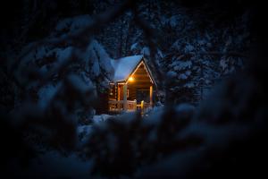 a cabin in the snow at night with lights on at Storm Mountain Lodge & Cabins in Banff