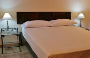 a bedroom with a large white bed with two lamps at Agriturismo Cavrigo in Lodi
