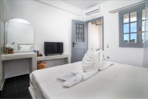 a bedroom with a bed with white sheets and a tv at Beach Houses Santorini in Kamari