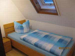 a bed with a blue and white pillow on it at Ferienwohnung Anna in Maroldsweisach