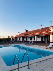 une grande piscine en face d'un bâtiment dans l'établissement Monte da Floresta B&B, à Ferreira do Alentejo