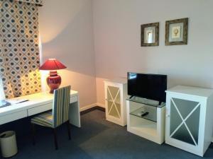 Habitación con escritorio, TV y lámpara. en Hotel Las Cigüeñas, en Trujillo
