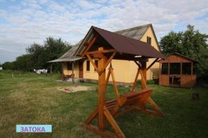 a wooden play structure in front of a house at Затока 1 in Svityazʼ