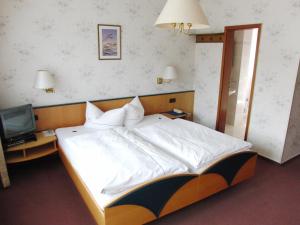 a bedroom with a large white bed and a television at Hotel Olympia in Bad Orb