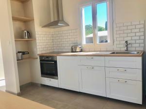 a kitchen with white cabinets and a sink and a window at Chez Georges - Maison 2 - Les Gîtes du Verdon in Esparron-de-Verdon