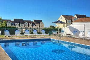 a swimming pool with chairs and a house in the background at Village By The Sea in Wells