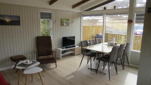 a dining room with a table and chairs and a television at Hvammur 1 with private hot tub in Drangsnes