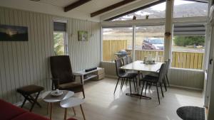 a dining room with a table and chairs and a window at Hvammur 1 with private hot tub in Drangsnes