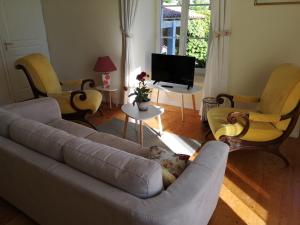 ein Wohnzimmer mit einem Sofa, Stühlen und einem TV in der Unterkunft Coté Marais - gite familial in Chaillé-les-Marais