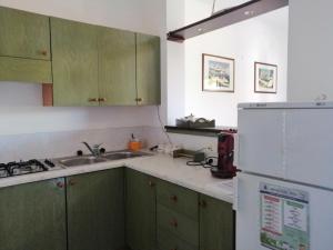 a kitchen with green cabinets and a white refrigerator at Casa Esperanto in Favignana