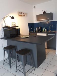 - une cuisine avec un comptoir noir et des tabourets dans l'établissement Talence, studio cosy 27 M2, Bordeaux 10 mn en tram, à Talence