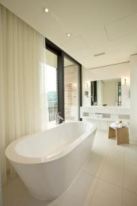 a white bathroom with a tub and a large window at Hotel Kloster Haydau in Morschen