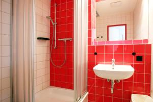 a red tiled bathroom with a sink and a shower at Jugendherberge-Berlin-International in Berlin